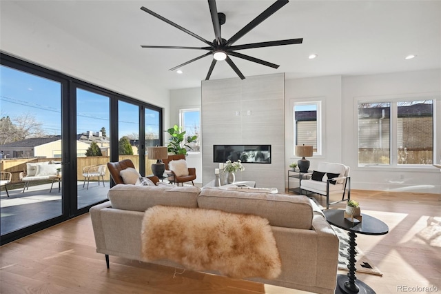 living room featuring a fireplace, a wealth of natural light, light hardwood / wood-style flooring, and ceiling fan