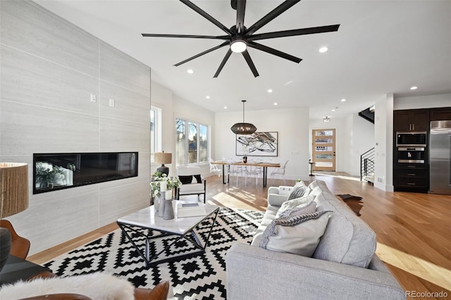 living room featuring a large fireplace, light hardwood / wood-style floors, and ceiling fan