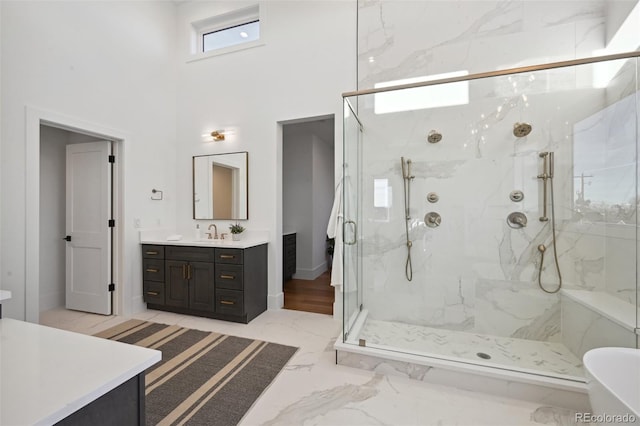 bathroom with vanity, shower with separate bathtub, and a towering ceiling