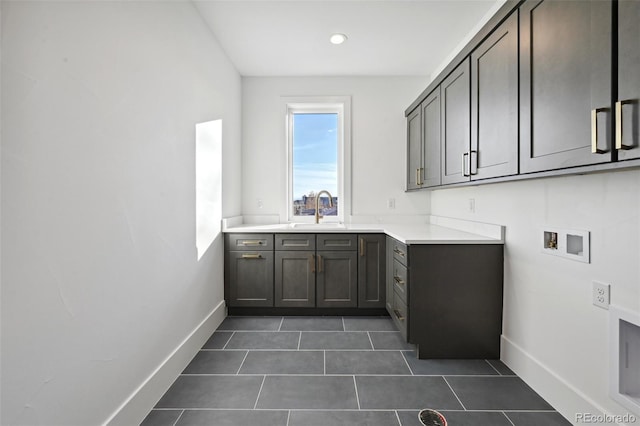 laundry area featuring washer hookup, cabinets, dark tile patterned floors, and sink