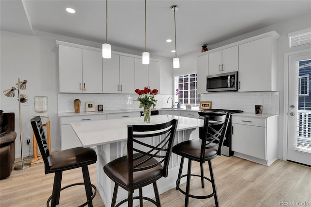 1086 Highlands Dr, Erie, CO 80516 - kitchen with appliances with stainless steel finishes, light countertops, light wood finished floors, a kitchen breakfast bar, and recessed lighting