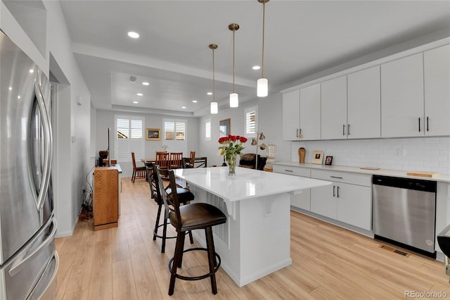 1086 Highlands Dr, Erie, CO 80516 - kitchen featuring appliances with stainless steel finishes, a kitchen bar, recessed lighting, light wood-style floors, and backsplash