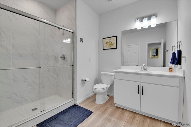 1086 Highlands Dr, Erie, CO 80516 - bathroom featuring toilet, a stall shower, baseboards, vanity, and wood finished floors
