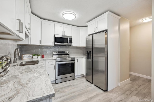 kitchen featuring light wood-type flooring, stainless steel appliances, white cabinetry, and sink