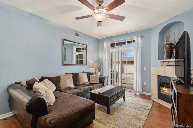 7440 S Blackhawk St Unit 2-106, Englewood, CO 80112 - living room with a tiled fireplace, ceiling fan, and wood finished floors