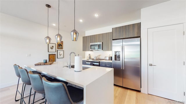 930 Blue River Pkwy Unit 622, Silverthorne, CO 80498 - kitchen featuring stainless steel appliances, light wood-style flooring, light countertops, a kitchen breakfast bar, and recessed lighting