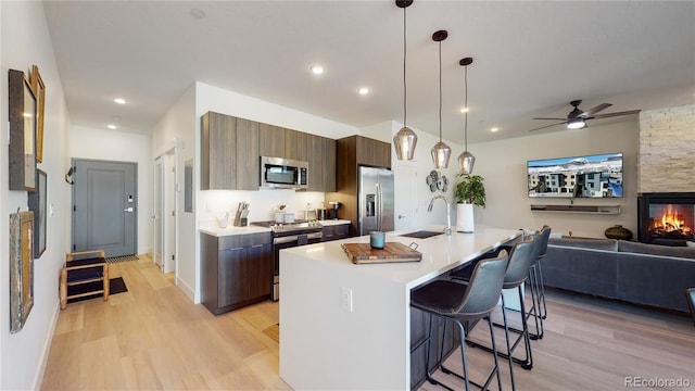 930 Blue River Pkwy Unit 622, Silverthorne, CO 80498 - kitchen with appliances with stainless steel finishes, a sink, open floor plan, light wood-style floors, and a breakfast bar