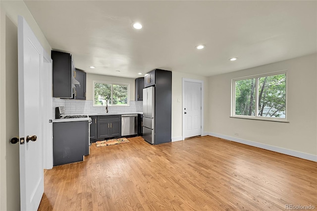 kitchen featuring stainless steel appliances, baseboards, tasteful backsplash, light countertops, and light wood-style floors