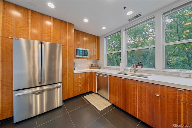 kitchen featuring backsplash, stainless steel appliances, sink, and dark tile patterned floors