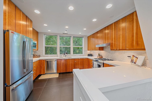 kitchen featuring tasteful backsplash, sink, dark tile patterned flooring, kitchen peninsula, and stainless steel appliances