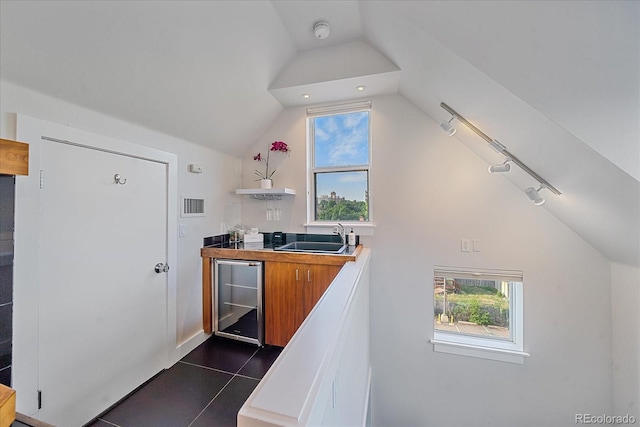 kitchen featuring lofted ceiling, sink, beverage cooler, and dark tile patterned floors