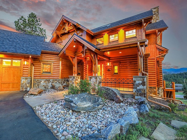 log-style house featuring covered porch and a garage