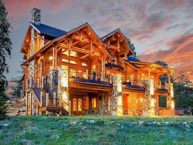 back house at dusk featuring a hot tub and a balcony