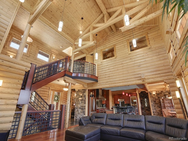 living room featuring ornate columns, hardwood / wood-style floors, beamed ceiling, rustic walls, and wooden ceiling