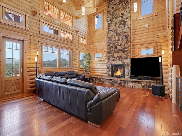 living room with hardwood / wood-style floors, wood ceiling, a stone fireplace, and a wealth of natural light