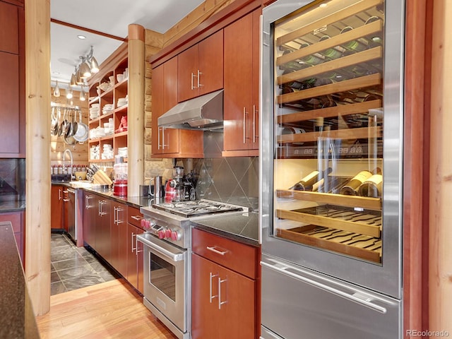 kitchen with wine cooler, light hardwood / wood-style flooring, high end stove, decorative backsplash, and exhaust hood