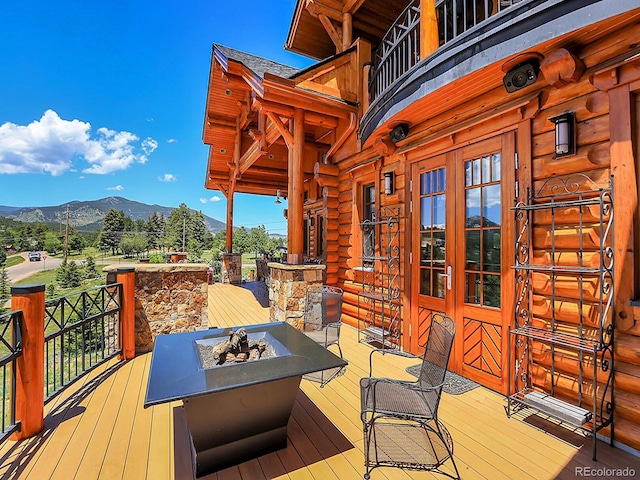 deck with french doors, a mountain view, and a fire pit