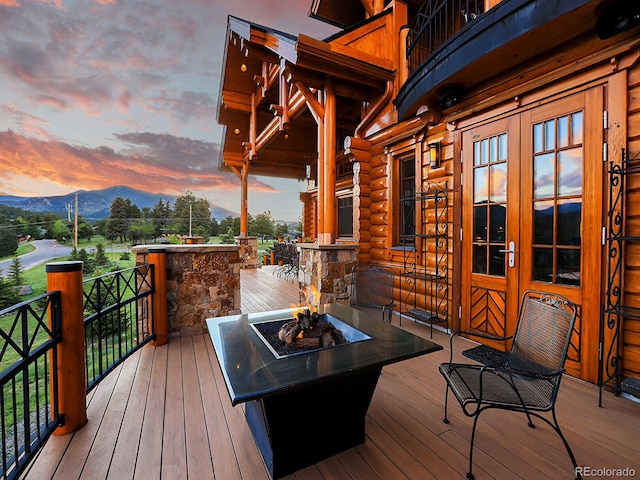 deck at dusk featuring french doors, an outdoor fire pit, and a mountain view