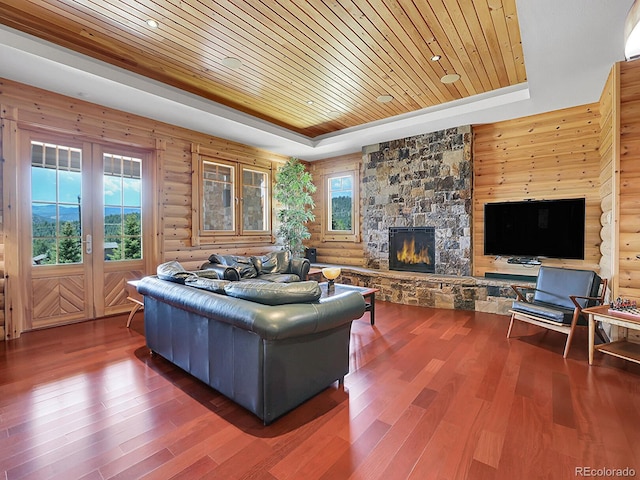 living room with dark hardwood / wood-style flooring, a tray ceiling, wooden ceiling, and a healthy amount of sunlight