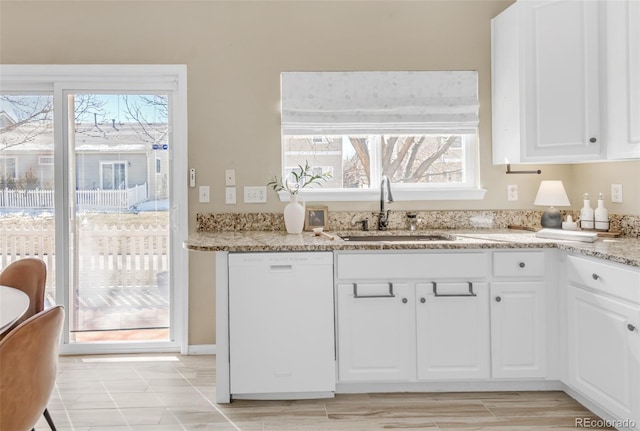 kitchen with a sink, white cabinetry, light stone counters, and dishwasher