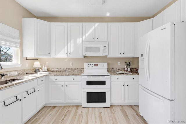 kitchen with white appliances, white cabinetry, light wood finished floors, and light stone counters