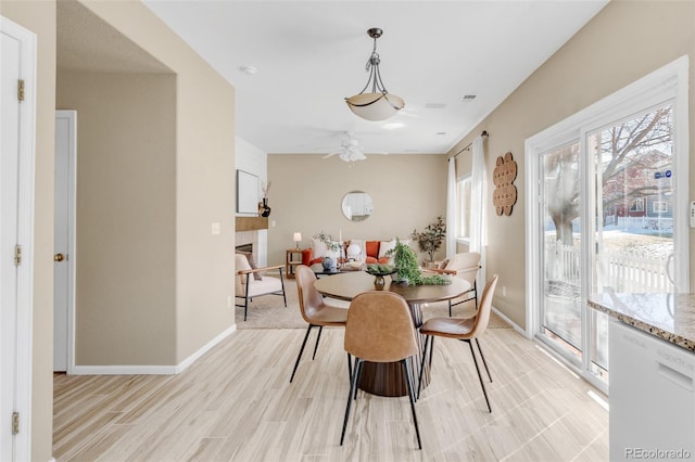 dining area with light wood-style floors, a fireplace, and baseboards