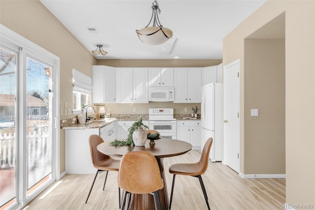 dining space featuring light wood-type flooring, visible vents, and baseboards