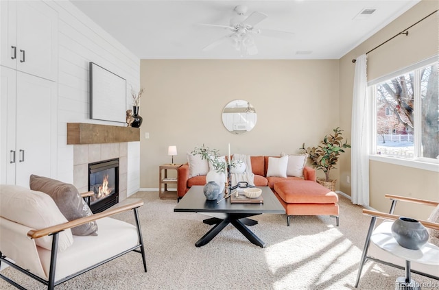 carpeted living area with a large fireplace, ceiling fan, visible vents, and baseboards