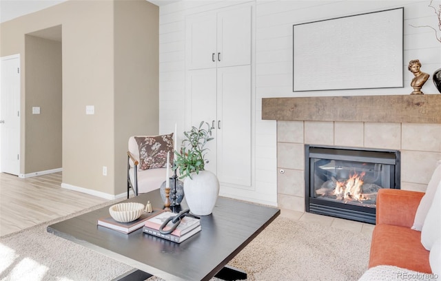 living area featuring a tiled fireplace, wood finished floors, and baseboards