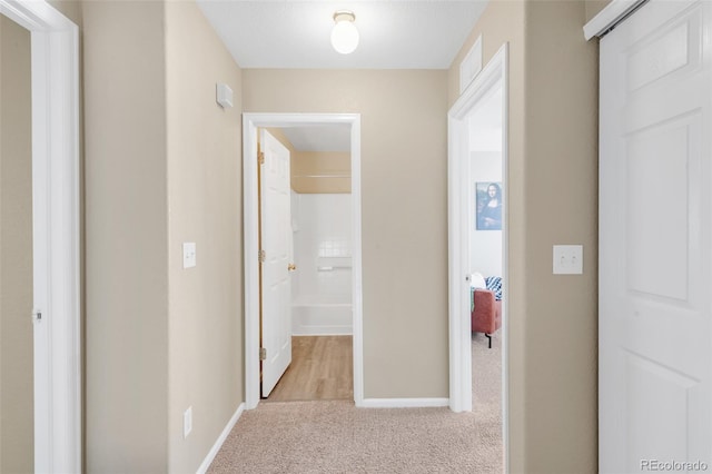 hall featuring carpet flooring and baseboards