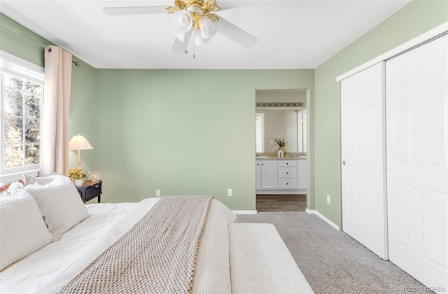 bedroom with carpet floors, a closet, ensuite bathroom, a ceiling fan, and baseboards