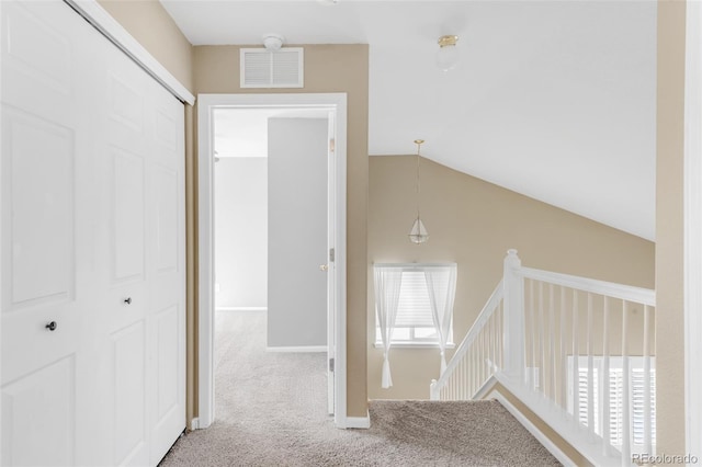 corridor featuring visible vents, baseboards, lofted ceiling, carpet, and an upstairs landing