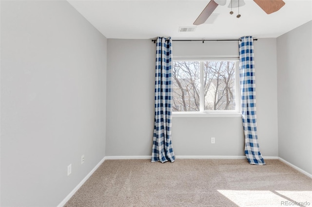 carpeted spare room with baseboards, visible vents, and a ceiling fan