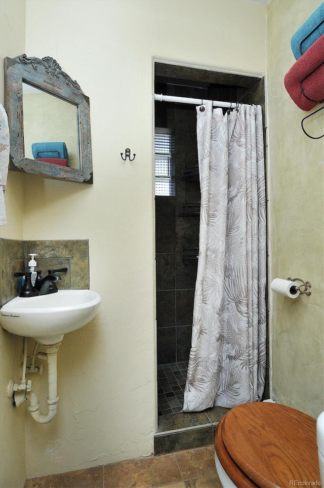 bathroom featuring walk in shower, toilet, tile floors, and sink