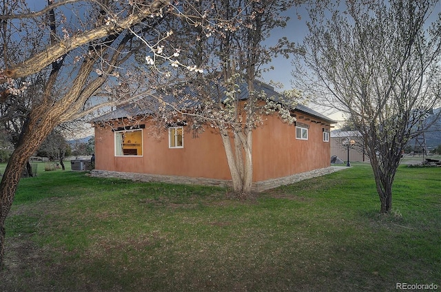 view of side of property with central AC and a lawn