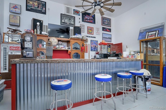 bar with ceiling fan and concrete flooring