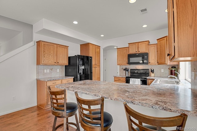 20826 Robins Dr, Denver, CO 80249 - kitchen with black appliances, a sink, a peninsula, decorative backsplash, and arched walkways