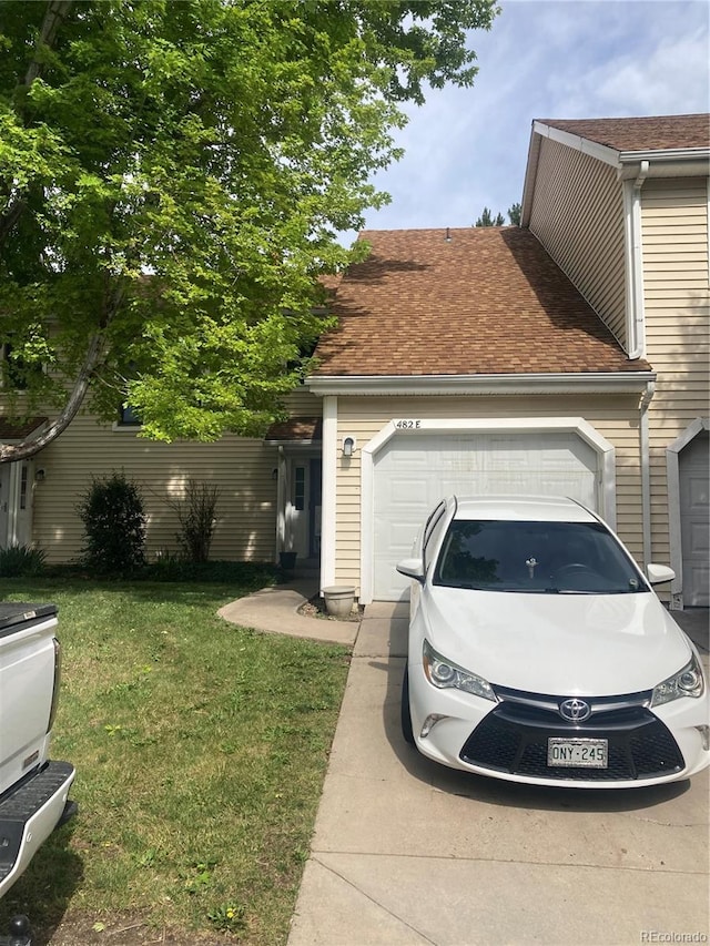 482 S Kalispell Way Unit E, Aurora, CO 80017 - view of side of property featuring an attached garage, a yard, a shingled roof, and driveway