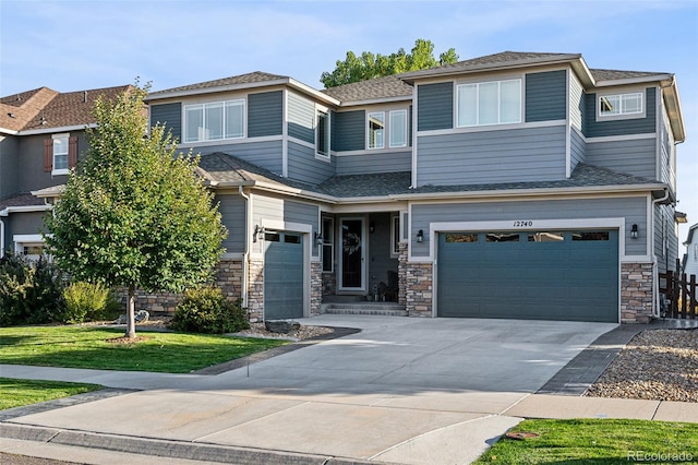 prairie-style house featuring a garage, stone siding, concrete driveway, and a front yard