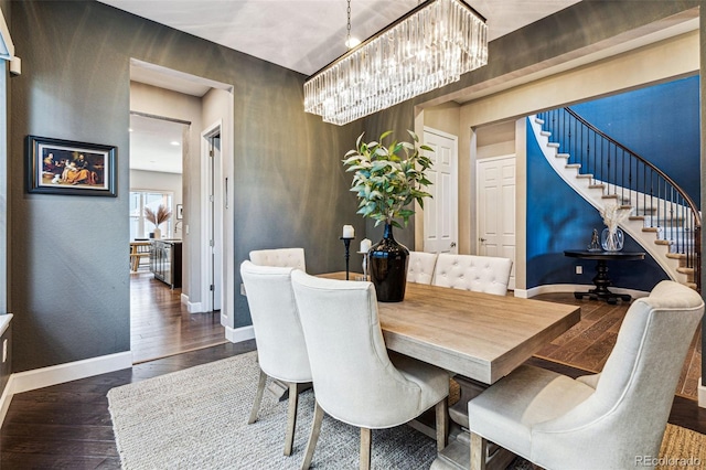 dining area featuring hardwood / wood-style flooring, stairs, baseboards, and a notable chandelier