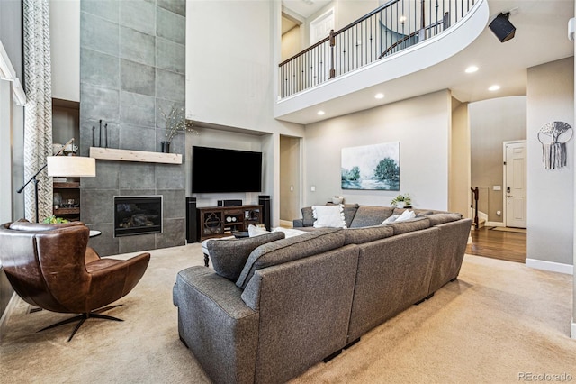 living area featuring recessed lighting, carpet floors, a high ceiling, baseboards, and a tiled fireplace