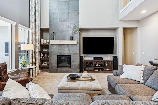 living room with a tile fireplace, carpet, and a high ceiling