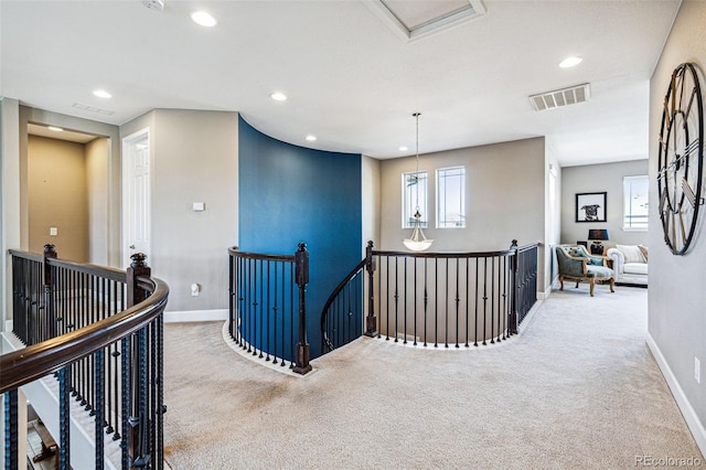 corridor featuring visible vents, carpet floors, and an upstairs landing