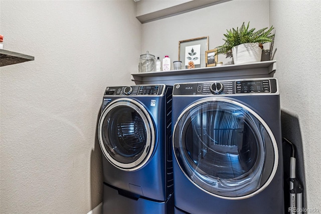 laundry area featuring a textured wall, laundry area, and washing machine and clothes dryer