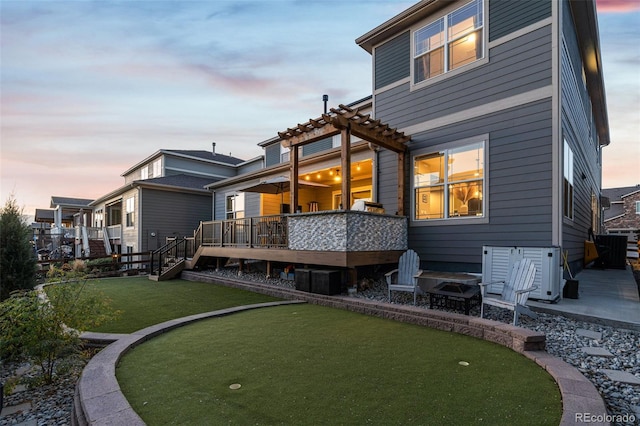 back of house at dusk featuring a patio, a wooden deck, and a pergola