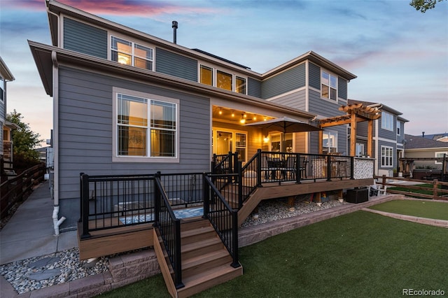 back of house at dusk featuring a deck and a yard