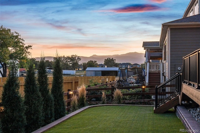 yard at dusk with stairway, fence, and a mountain view