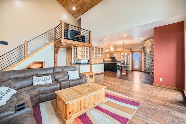 living room with recessed lighting, light wood-style flooring, high vaulted ceiling, and stairway