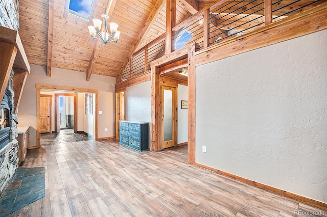 unfurnished living room featuring beamed ceiling, baseboards, a notable chandelier, and hardwood / wood-style floors