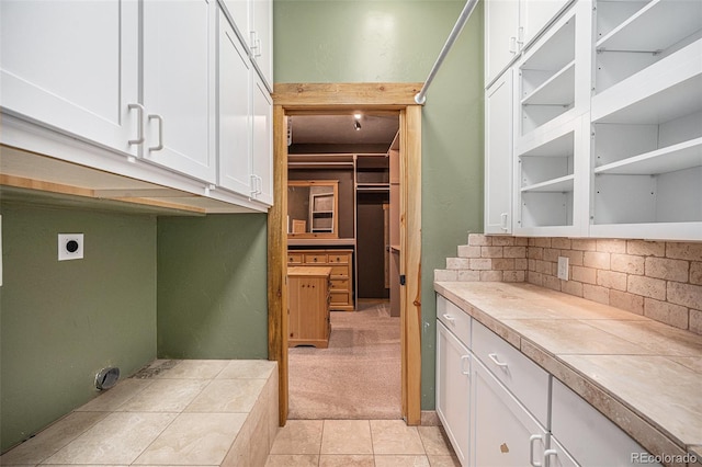 interior space with light tile patterned floors, electric dryer hookup, cabinet space, and light colored carpet